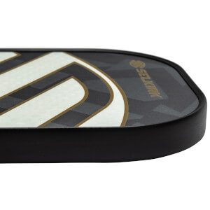 Side view of a black pickleball paddle with white and gold curved lines and Selkirk branding.