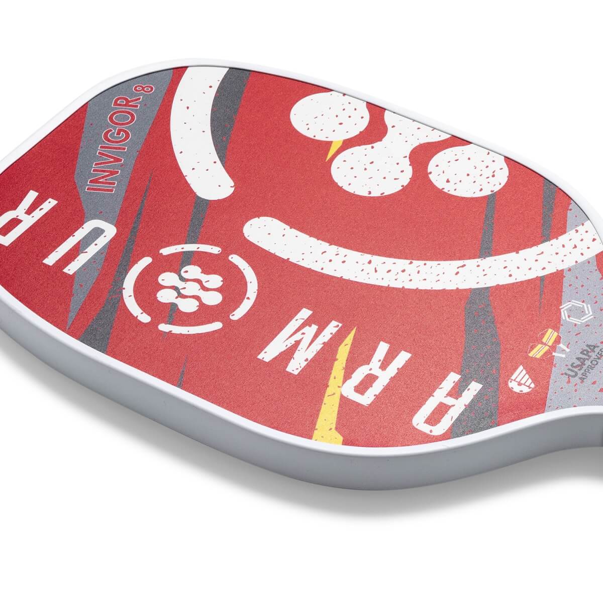 Corner view of a red pickleball paddle with ARMOUR INVIGOR8 text and a speckled pattern.