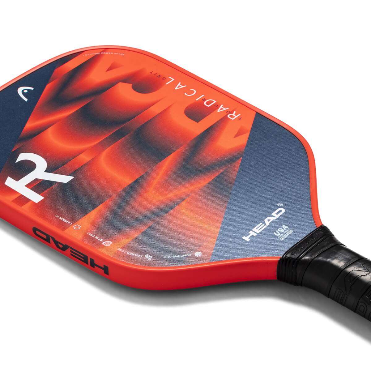 Corner view of a red pickleball paddle with a blue and orange abstract design, HEAD logo, and RADICAL-GRIT text.