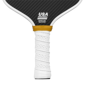 Close-up of a white pickleball paddle grip with perforations and a gold band above the USA Pickleball Approved logo.
