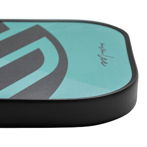 Corner view of a teal pickleball paddle with a black edge and a signature.