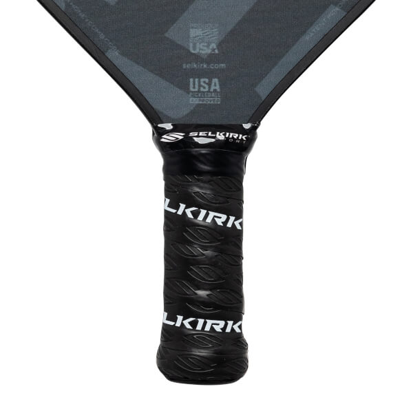 Close-up of a black pickleball paddle grip with Selkirk branding and leaf pattern.