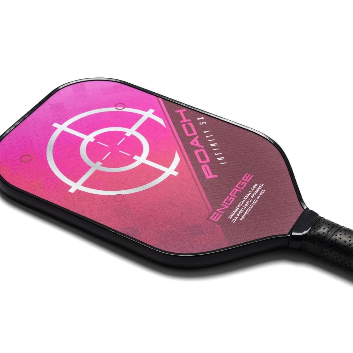 Top-down view of a pink pickleball paddle with a target design and POACH INFINITY SX text.