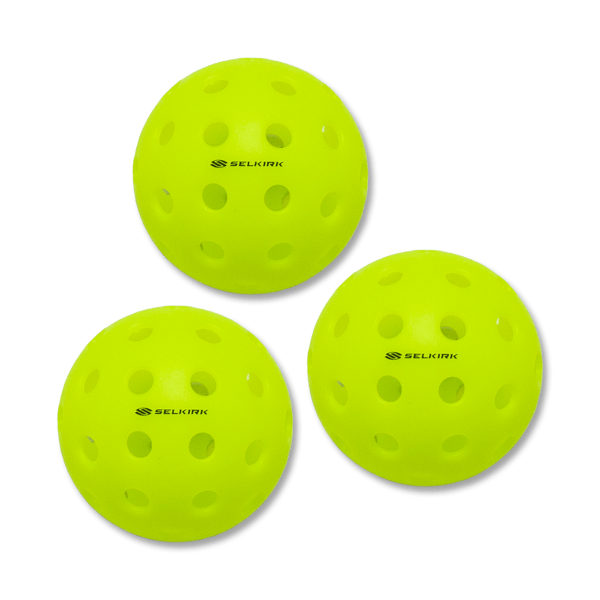 Top-down view of three neon yellow pickleballs, each with circular holes and a "SELKIRK" logo.