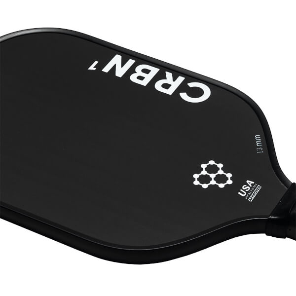 Corner view of a black pickleball paddle with white CRBN¹ branding, a molecular graphic, and USA Pickleball Approved text.