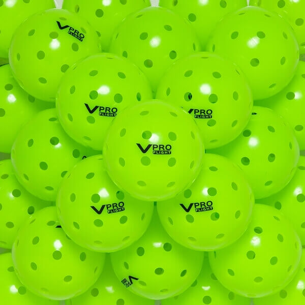 Close-up of lime green pickleballs with V PRO FLIGHT logo and circular perforations.