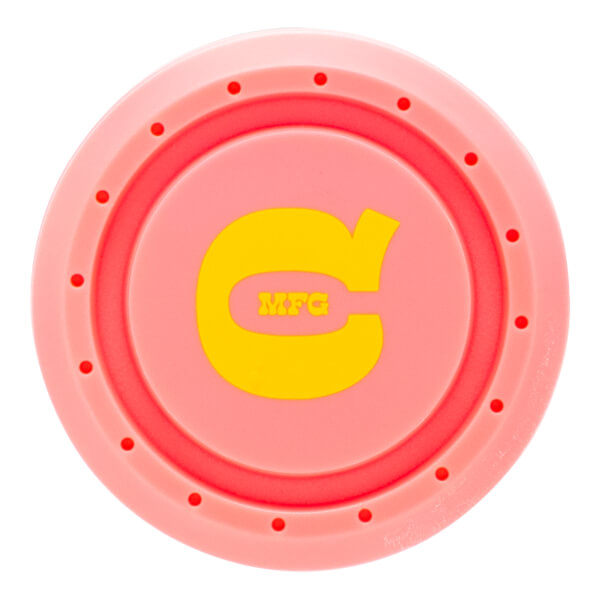 Top-down view of the pink bat knob featuring a yellow stylized "C" logo with "MFG" in the center and a ring of small circular indentations.