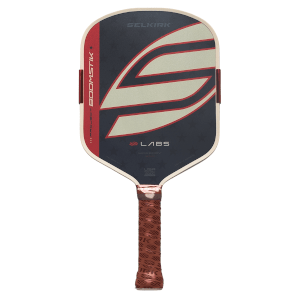 Front view of a Selkirk Labs Project Boomstik pickleball paddle featuring a large stylized cream S logo on a black and red face with a brown textured grip.