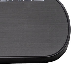 Close-up of a dark gray pickleball paddle with a textured surface, a black edge guard, and partial white lettering.