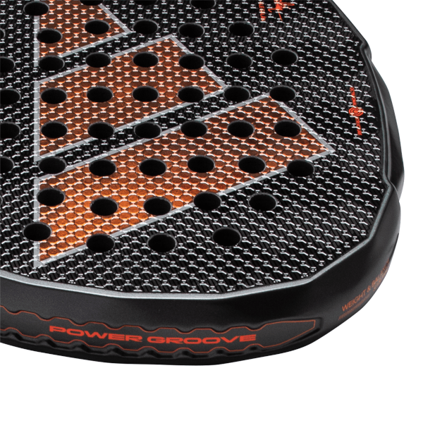 Close-up view of a black padel racket face showing orange geometric accents, black honeycomb texture, and red "POWER GROOVE" lettering.