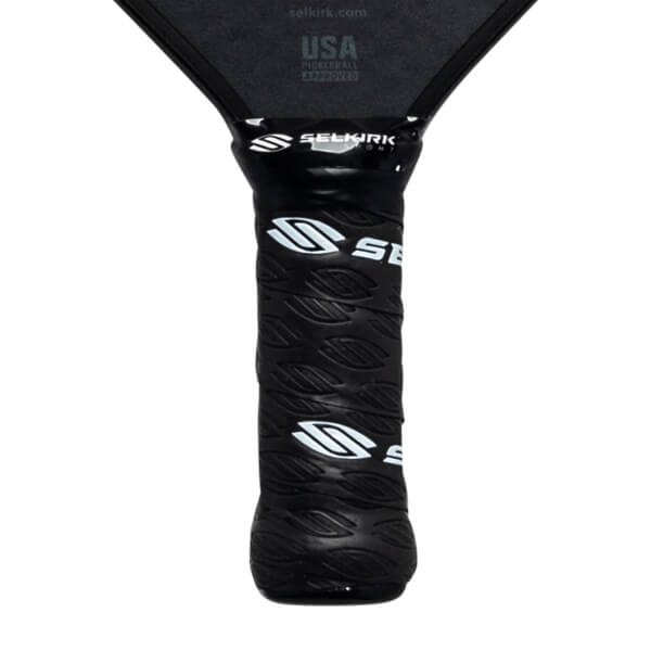 Close-up of a black pickleball paddle grip with white Selkirk logos and leaf-like texture.