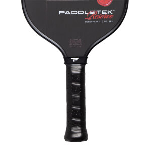 Partial front view of a black Paddletek Reserve pickleball paddle showing its branded face and a perforated black grip.