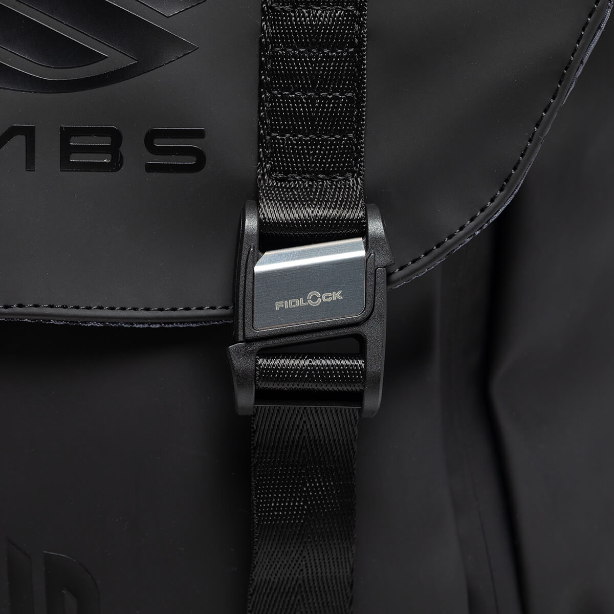 Close-up of the black Fidlock buckle and textured strap, featuring the FIDLOCK logo and partial LABS branding embossed on the matte black material.