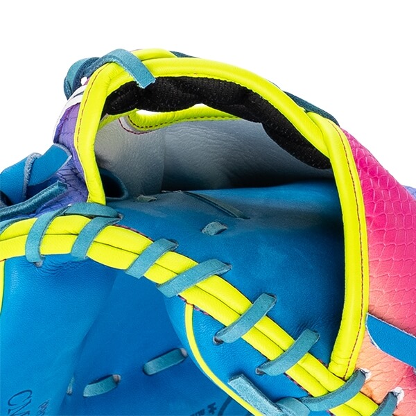 Close-up of the wrist opening and heel featuring bright yellow binding, teal lacing, blue leather, and a pink scale-textured pattern on the shell.