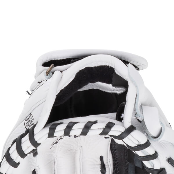 Close-up view of a white baseball glove's wrist opening featuring black laces and a stamp that reads MADE IN MEXICO.