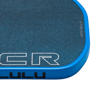 Close-up of a blue paddle's edge showing speckled grip, "LULU" text, and white lettering.