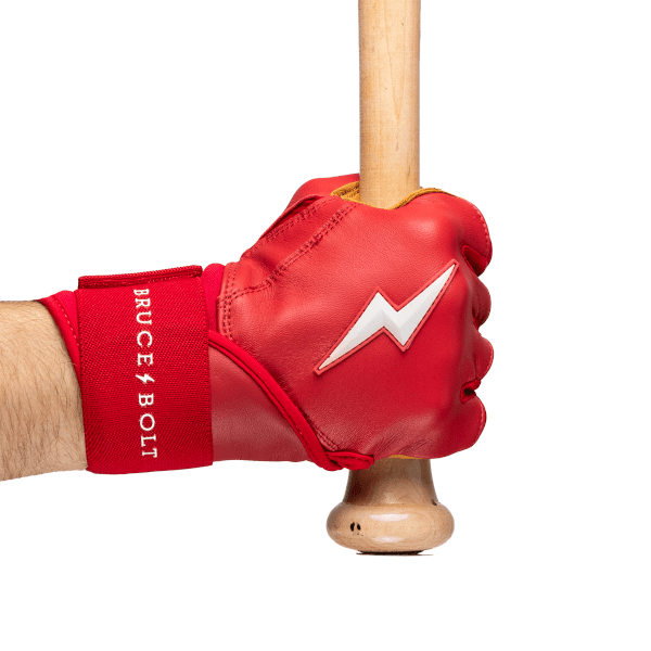 Close-up of a red batting glove with a white lightning bolt logo, gripping a wooden bat, with "BRUCE BOLT" text on the wrist strap.