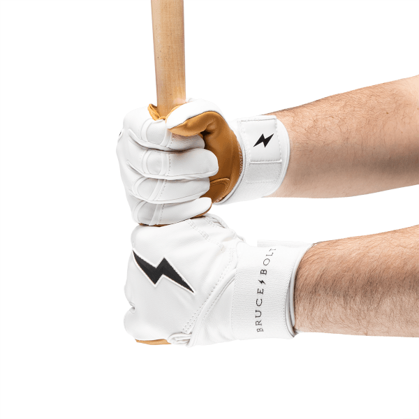 Front view of hands holding a baseball bat wearing white batting gloves with brown leather accents, black lightning bolt logos, and "BRUCE BOLT" text.