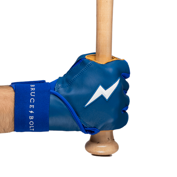 Side view of a blue batting glove with a white lightning bolt logo and "BRUCE BOLT" text on the wrist strap, gripping a wooden baseball bat.