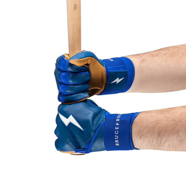 Close-up view of two blue batting gloves on hands, showing white lightning bolts and "BRUCE BOLT" text.