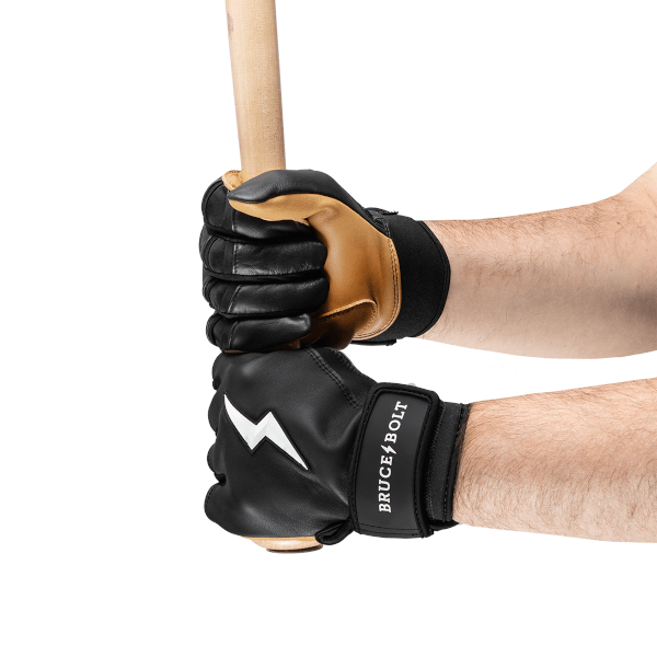 Close-up of black batting gloves with white lightning bolts and "BRUCE BOLT" branding gripping a wooden baseball bat.