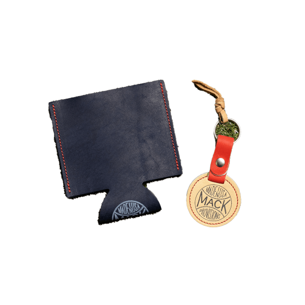 Front view of a navy blue leather can cooler with red stitching and a circular leather keychain that reads "MACK PROVISIONS MADE IN USA".