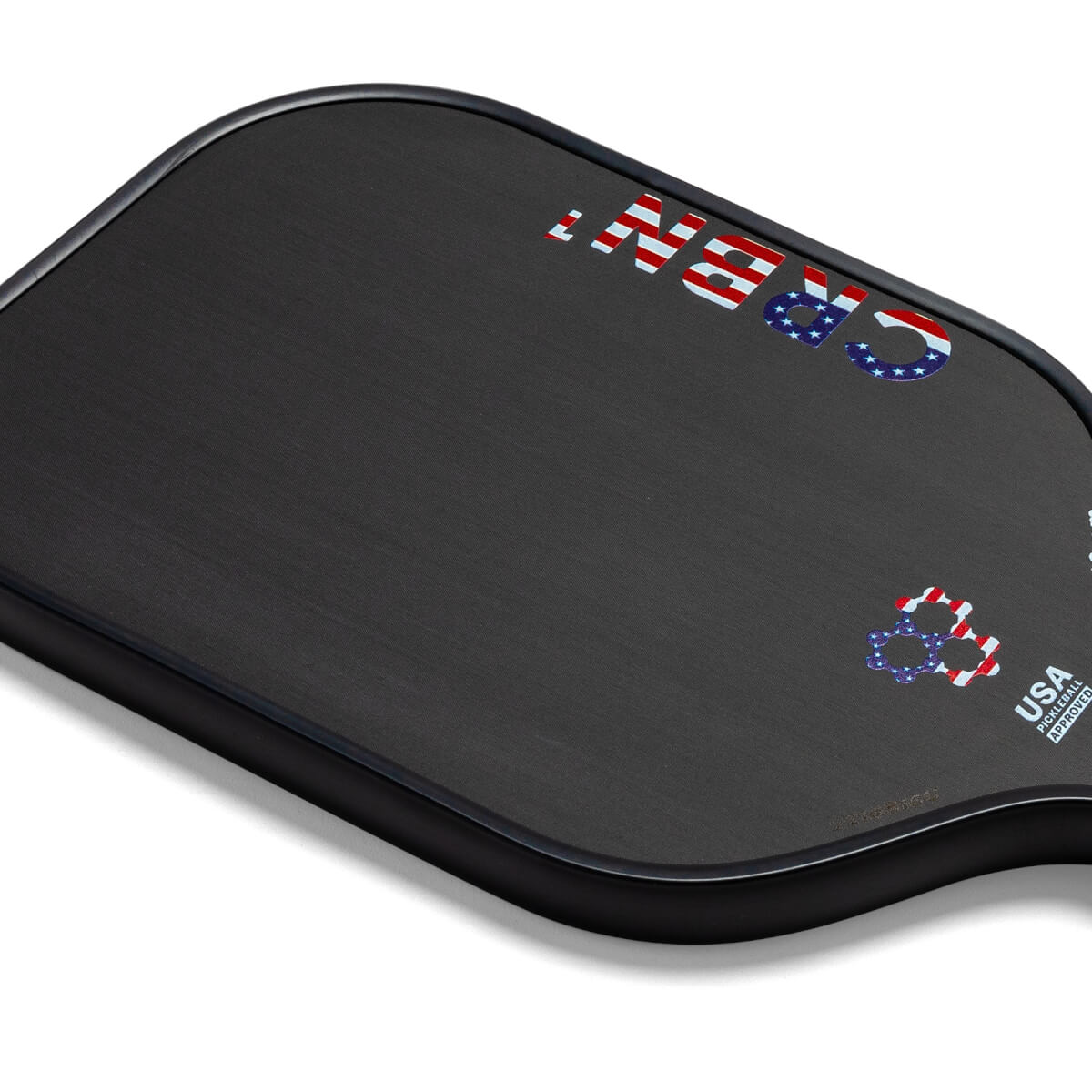 Corner view of a black pickleball paddle with American flag accents and CRBN text.