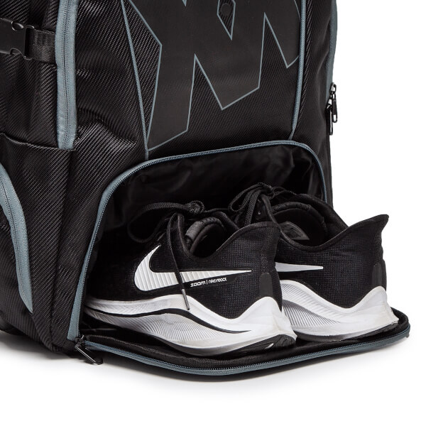 Close-up of a black backpack shoe compartment with two black Nike running shoes with white swooshes and zoom | nlereact text.