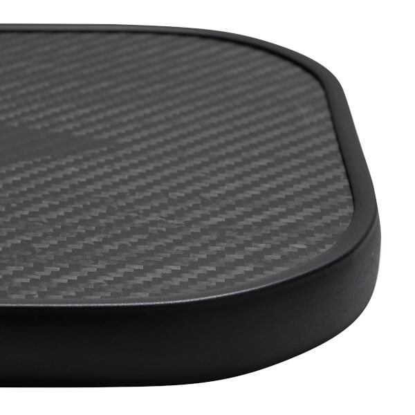 Close-up of a black pickleball paddle with a carbon fiber surface and black edge.