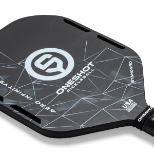 Top-down view of a black pickleball paddle with a white geometric pattern, ONESHOT PICKLEBALL text, and USA PICKLEBALL APPROVED stamp.