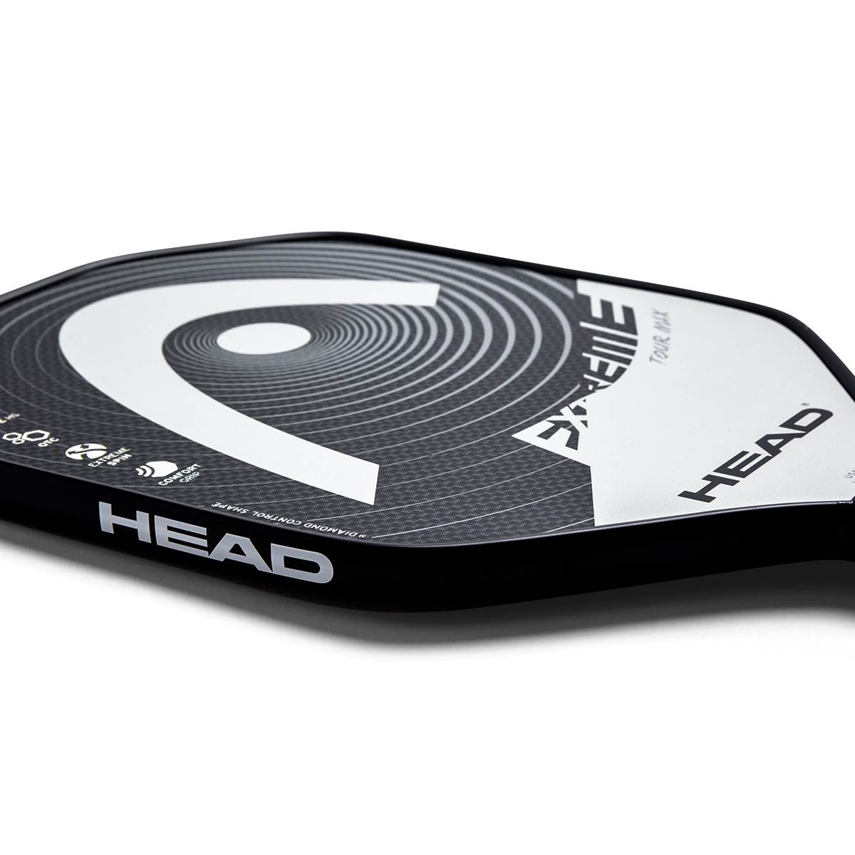 Corner view of a black pickleball paddle with a large white HEAD logo, EXTREME TOUR MAX text, and carbon fiber texture.