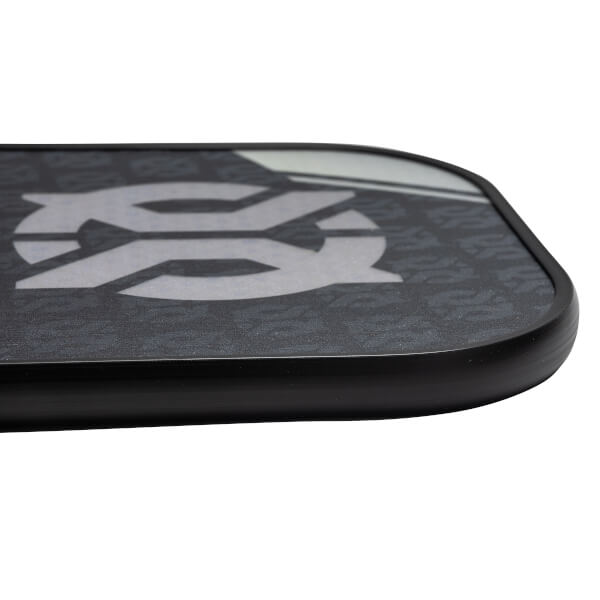 Corner view of a black pickleball paddle with a large white SS logo and repeating pattern.