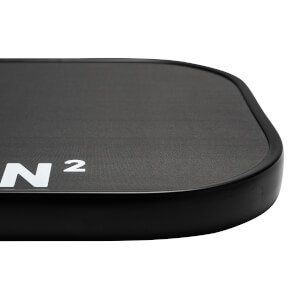 Corner view of a black pickleball paddle with white N and 2 branding and a textured surface.