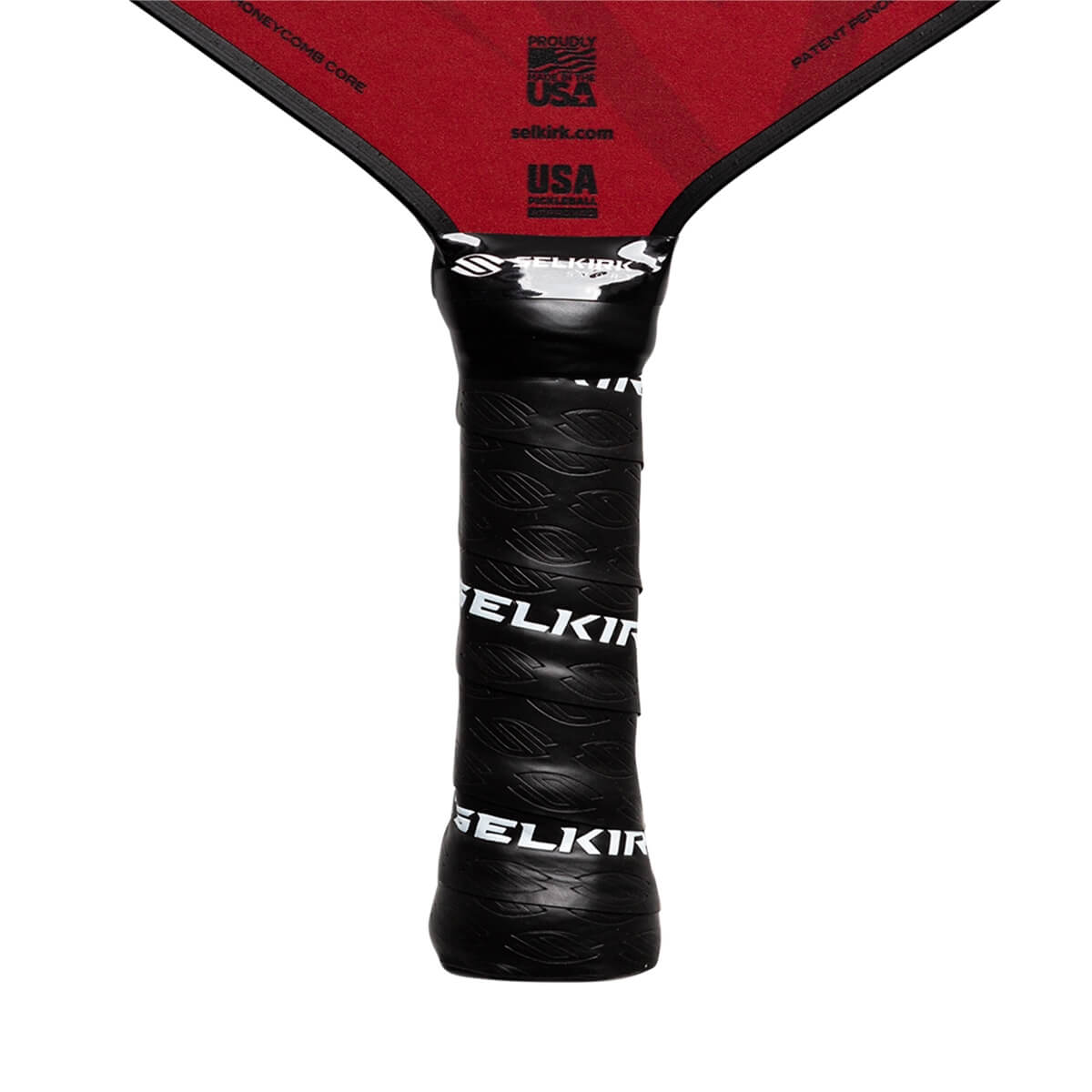 Close-up of a black pickleball paddle grip with Selkirk branding and a red paddle head with USA markings.