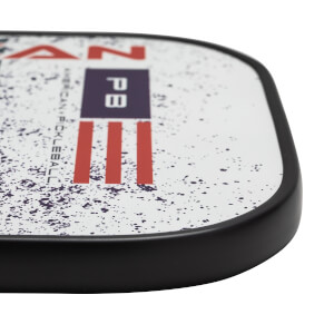 Corner view of a white pickleball paddle with red and blue PB logo and American flag design.