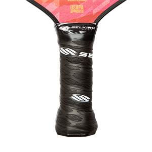 Close-up of a black pickleball paddle grip with leaf pattern and white SE logo.
