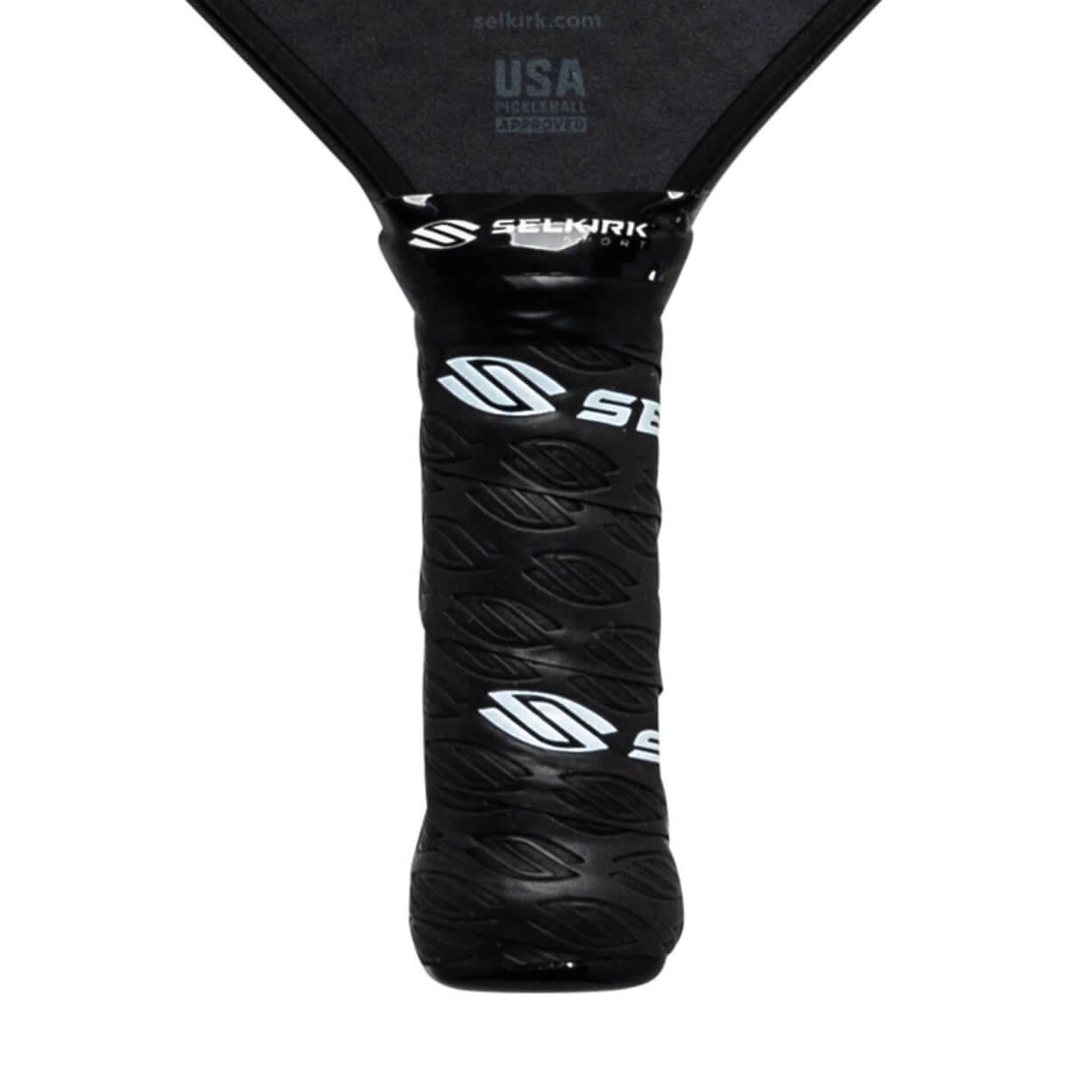 Close-up of a black pickleball paddle grip with white Selkirk logos and leaf-like texture.