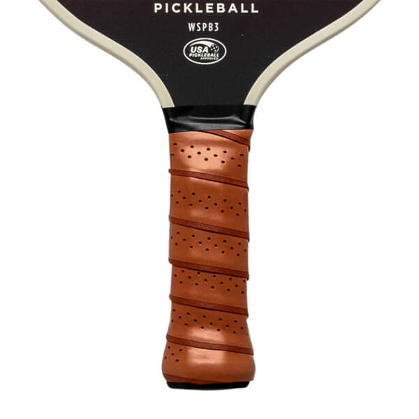 Top-down view of a black pickleball paddle with a brown perforated grip and USA Pickleball branding.
