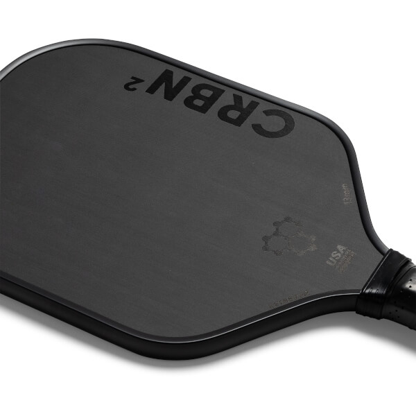 Top-down view of a black pickleball paddle with CRBN² branding and a textured surface.