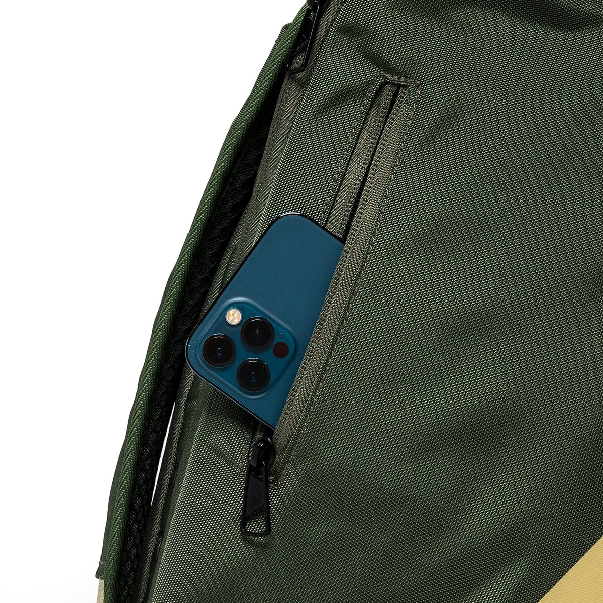 Close-up view of the green backpack featuring a blue smartphone partially tucked into a vertical zippered side pocket.