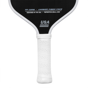 Top-down view of a black pickleball paddle with white grip, USA PICKLEBALL APPROVED text, and PBPROPICKLEBALL.COM website.