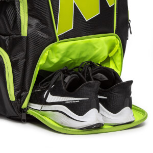 Close-up of a black pickleball backpack with neon green lining and a pair of black Nike shoes with white swooshes.