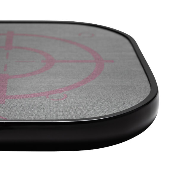 Corner view of a grey pickleball paddle with a pink target design and black edge.