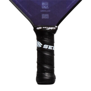 Close-up of a black pickleball paddle grip with white Selkirk branding and USAPA Approved text on the purple paddle head.