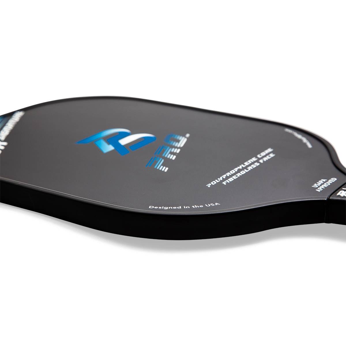 Side view of a black pickleball paddle with blue PB PRO logo, POLYPROPYLENE CORE FIBERGLASS FACE text, and USAPA APPROVED stamp.