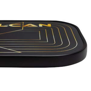 Corner view of a black pickleball paddle with gold geometric lines and LCAN text.