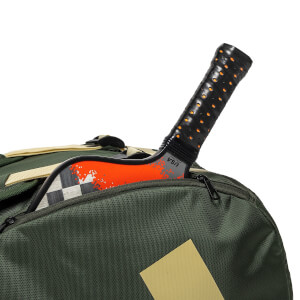 Close-up of an olive green bag with a pickleball paddle inside, showing a black handle and an orange patterned face that reads "USA PICKLEBALL APPROVED."