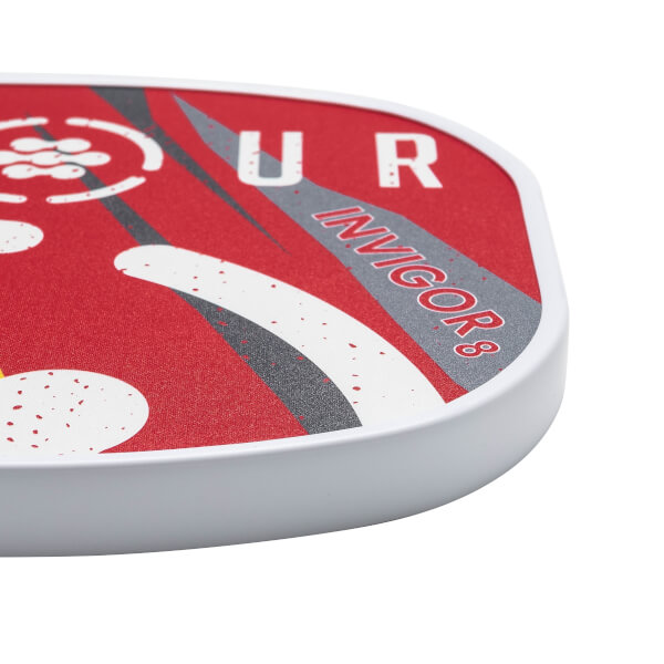 Corner view of a red pickleball paddle with INVIGOR8 text and white edge.