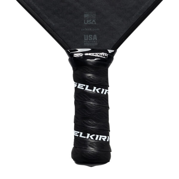 Close-up of a black pickleball paddle grip with white Selkirk branding.