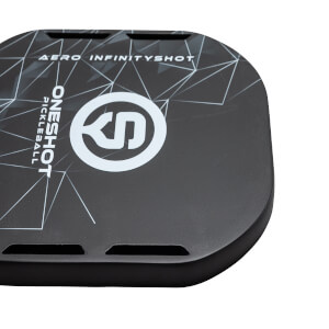 Top-down view of a black pickleball paddle with white ONESHOT PICKLEBALL text, a circular logo, and AERO INFINITYSHOT text.